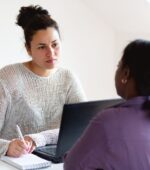 A social workers listens to a patient and takes notes