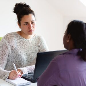 A social workers listens to a patient and takes notes