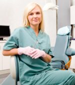 A dental hygienist posing in a dentist's office