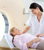 A medical professional helps a patient into an MRI machine